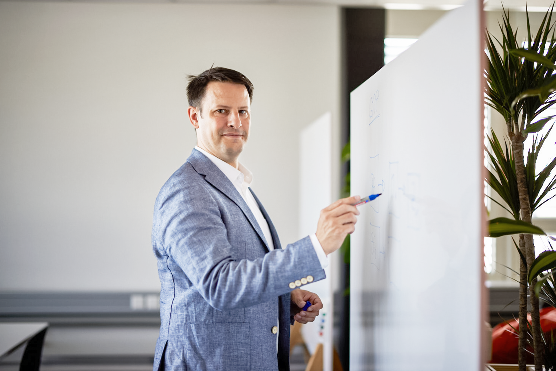 iqual Mitarbeiter steht vor dem Whiteboard