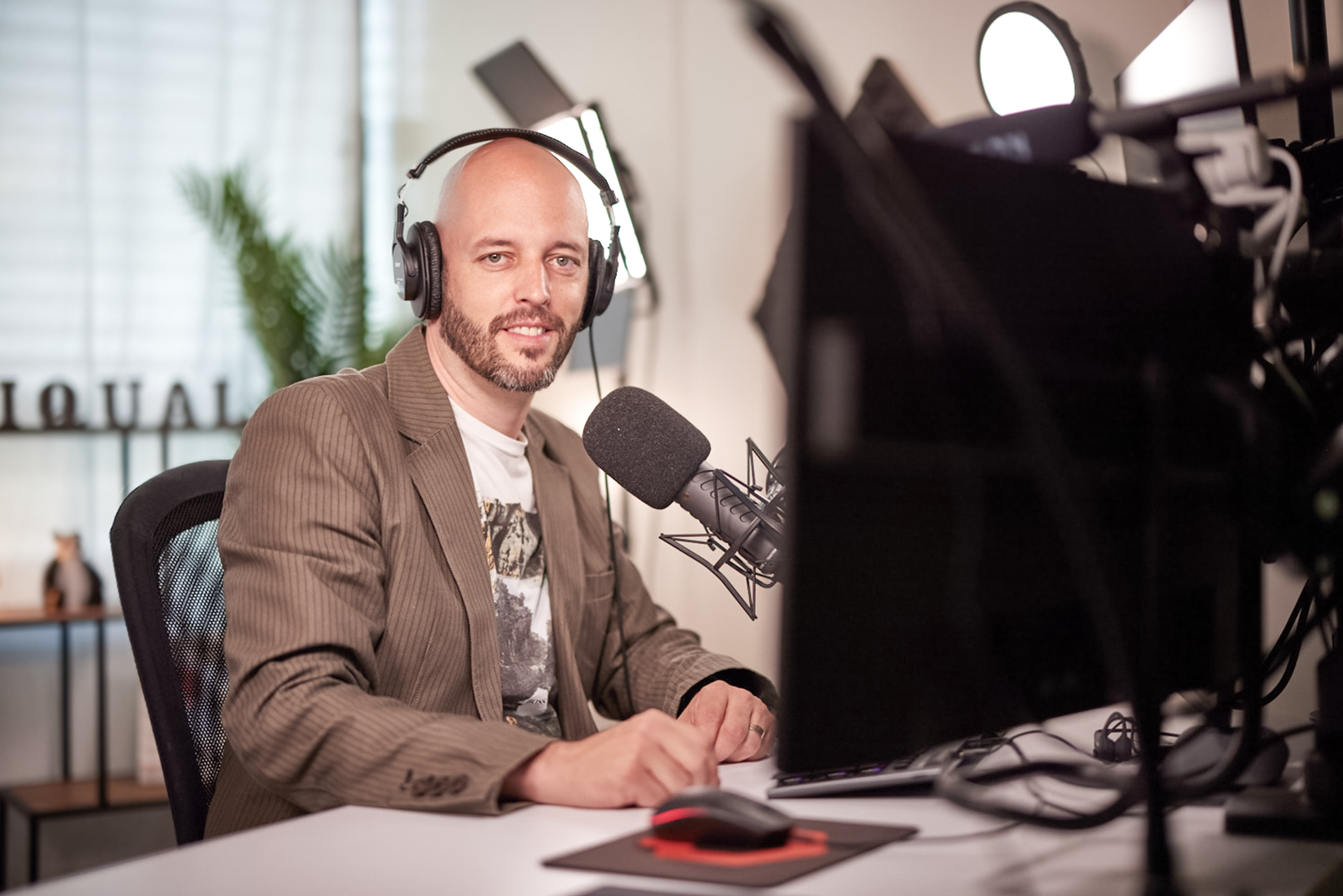 iqual Mitarbeiter sitzt mit Kopfhörern am Mikrofon
